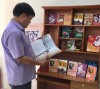 Thầy giáo Nguyễn Khắc Thành đang đọc sách tại tủ sách Bác Hồ trường THCS Dân Hòa